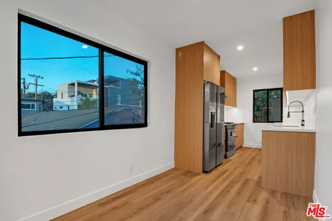 a view of a kitchen with a refrigerator a sink wooden floor and a window