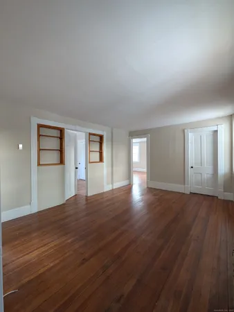 a view of an empty room with window and wooden floor