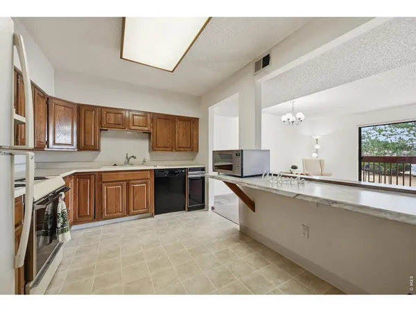 a large kitchen with a large counter top space a sink stainless steel appliances and cabinets