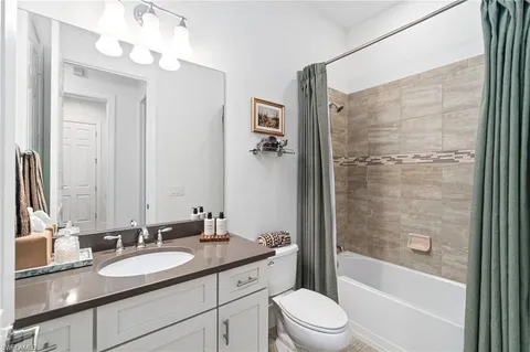 a bathroom with a bathtub shower sink vanity mirror and toilet