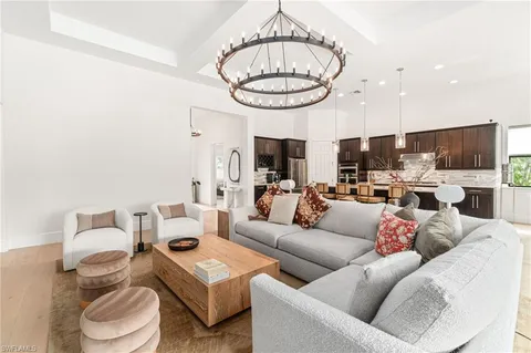 a living room with furniture a kitchen view and a chandelier