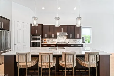 a kitchen with stainless steel appliances kitchen island granite countertop a stove a refrigerator and wooden cabinets