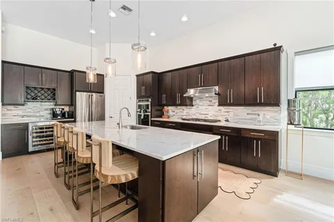 a kitchen with stainless steel appliances kitchen island granite countertop a sink refrigerator and cabinets