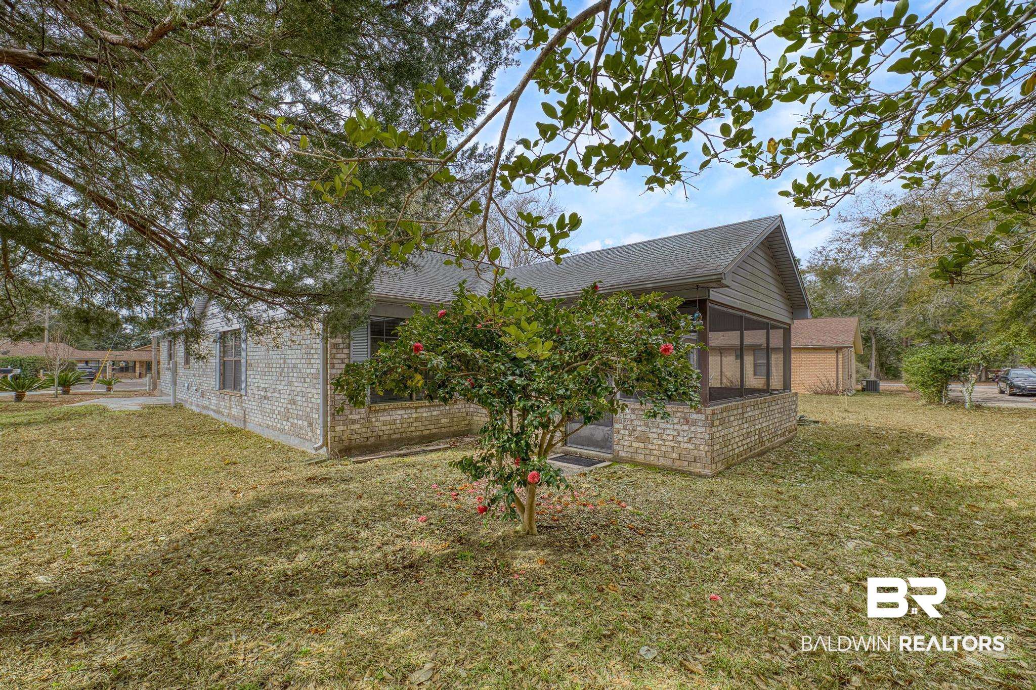 2776 Santa Rosa Circle Lillian, AL 36549 - Photo 3 of 48 Rear view of property featuring a sunroom, a lawn, a shingled roof, and brick siding