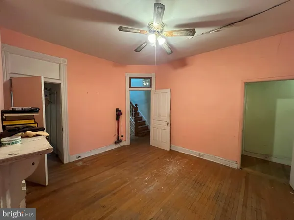 a view of an empty room with wooden floor and windows