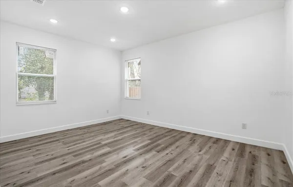an empty room with wooden floor and windows