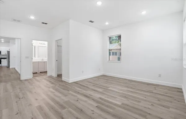 an empty room with wooden floor and windows