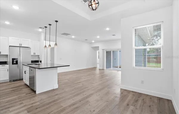 a kitchen with stainless steel appliances granite countertop a refrigerator a sink dishwasher a stove and a wooden floors