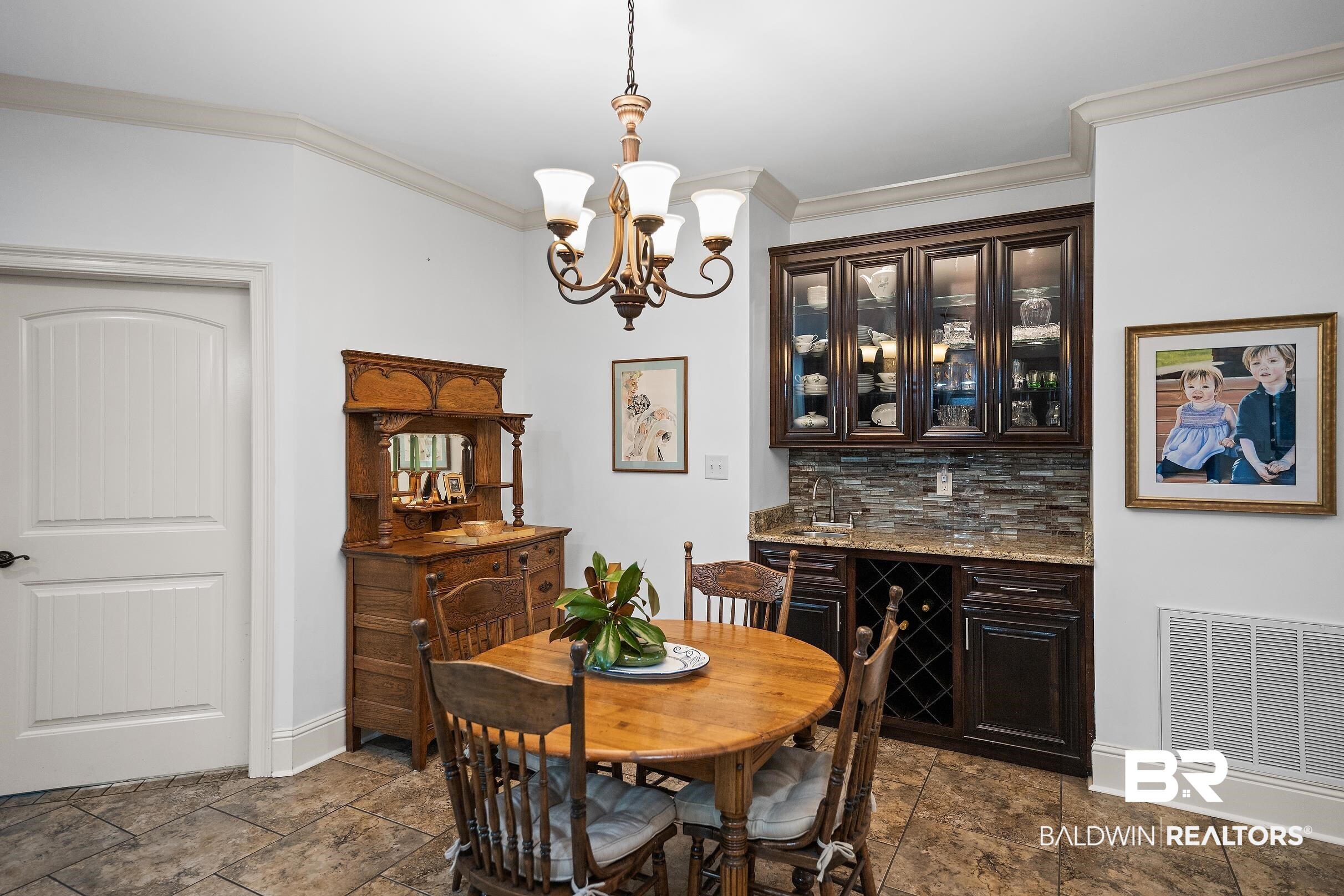 313 Pecan Ridge Boulevard Fairhope, AL 36532 - Photo 8 of 51 Integrated wet bar featuring dark wood cabinetry, glass-front upper cabinets, a stone countertop, and a mosaic tile backsplash