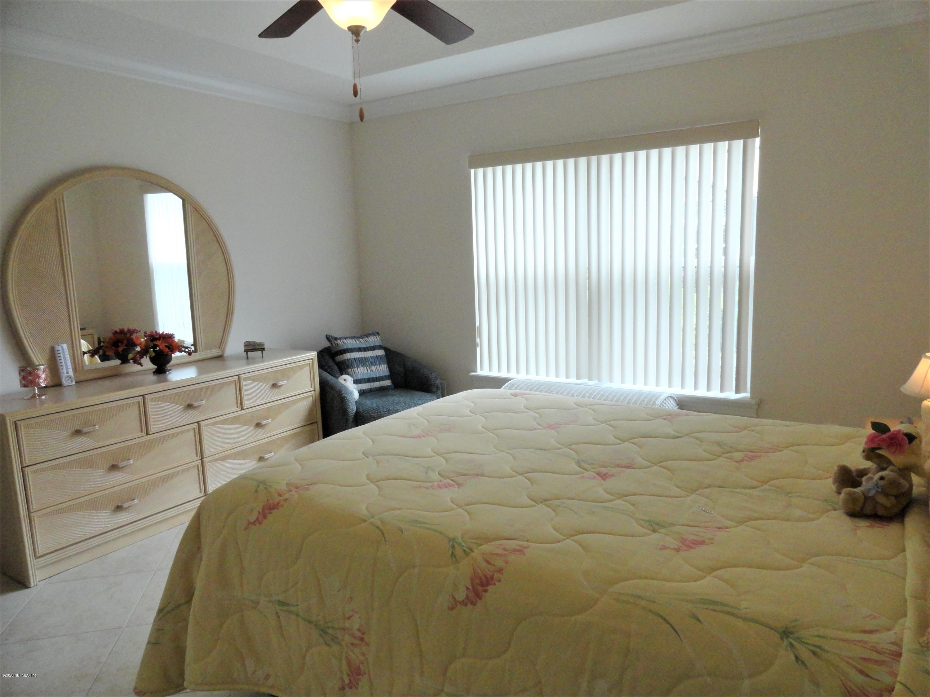 33 Utina Way St. Augustine, FL 32084 - Photo 22 of 30 a bedroom with a bed and a chandelier