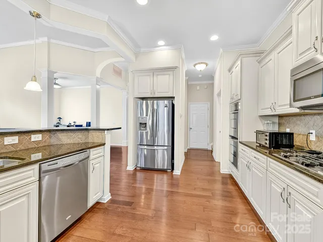 a large kitchen with stainless steel appliances kitchen island granite countertop a stove a sink and a refrigerator