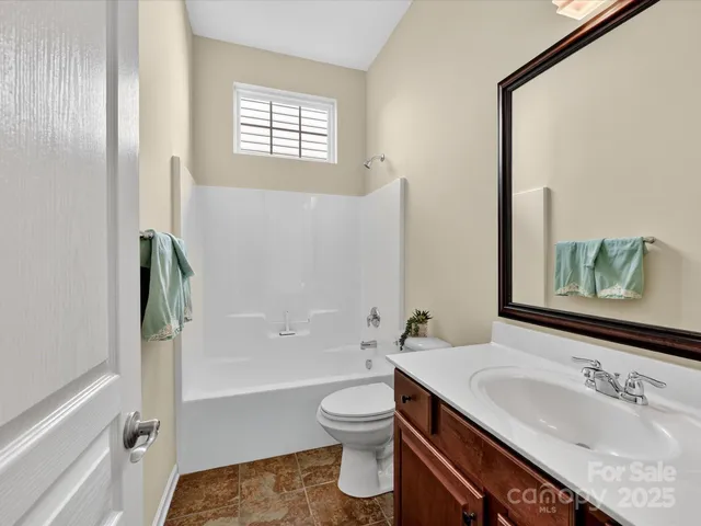 a bathroom with a granite countertop sink toilet a large mirror and shower