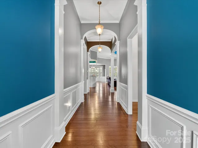 a hallway with wooden floor chandelier and entryway