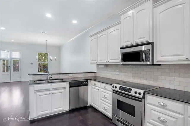 a kitchen with white cabinets and appliances