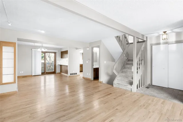 a view of an empty room with window and wooden floor