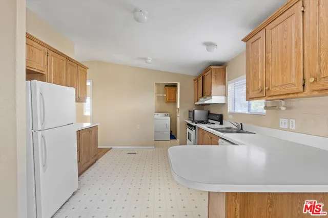 a kitchen with a refrigerator a stove a sink a counter space and cabinets