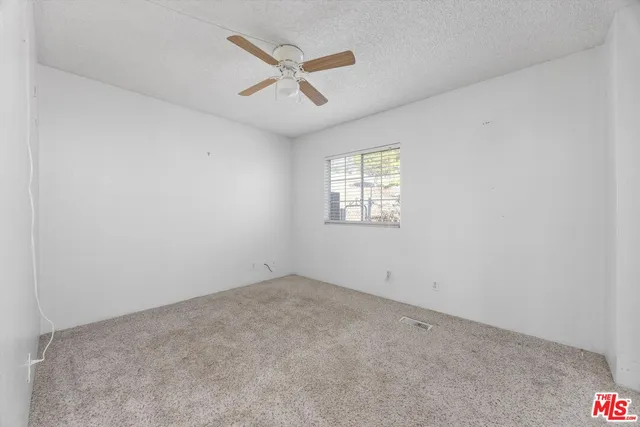 an empty room with a window and ceiling fan