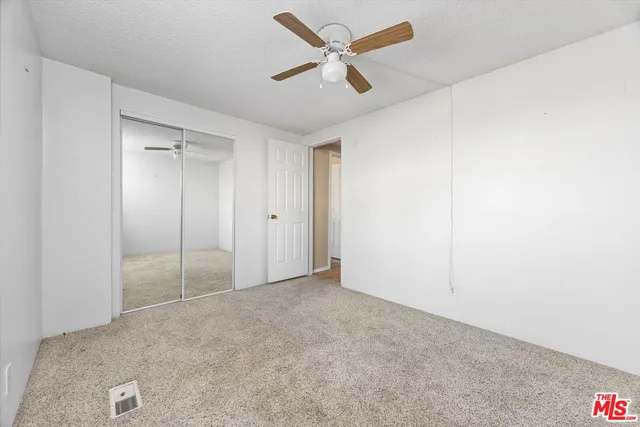 an empty room with closet and fan