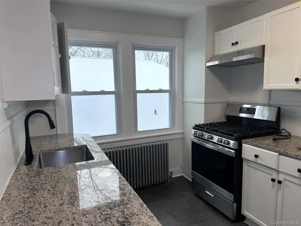 a kitchen with granite countertop a stove and a sink