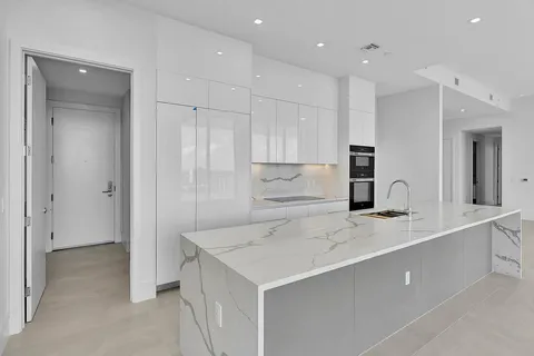 a kitchen with a sink a center island stainless steel appliances and cabinets