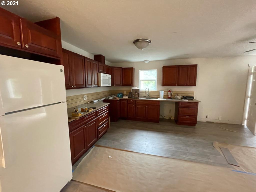 5720 Southeast Jenne Road Portland, OR 97236 - Photo 7 of 23 a kitchen with stainless steel appliances granite countertop a refrigerator stove a sink dishwasher and a refrigerator with wooden cabinets
