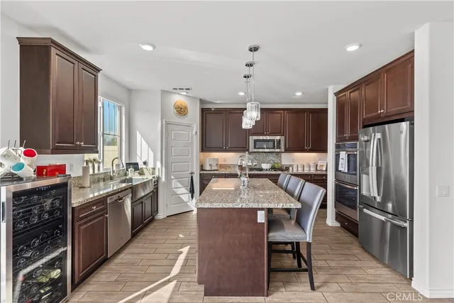 a kitchen with stainless steel appliances kitchen island granite countertop a sink refrigerator and cabinets