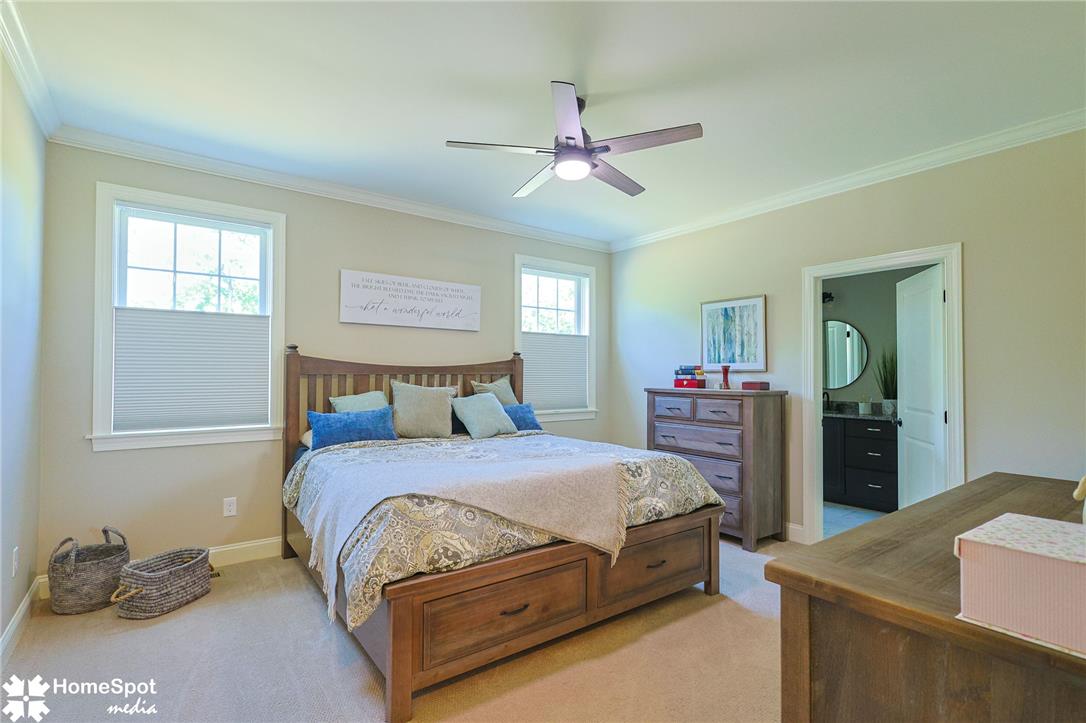 4518 Old Saucon Road Bethlehem, PA 18015 - Photo 9 of 19 A well-lit bedroom features crown molding, a ceiling fan, and carpeted floors, with a glimpse of an en-suite bathroom.