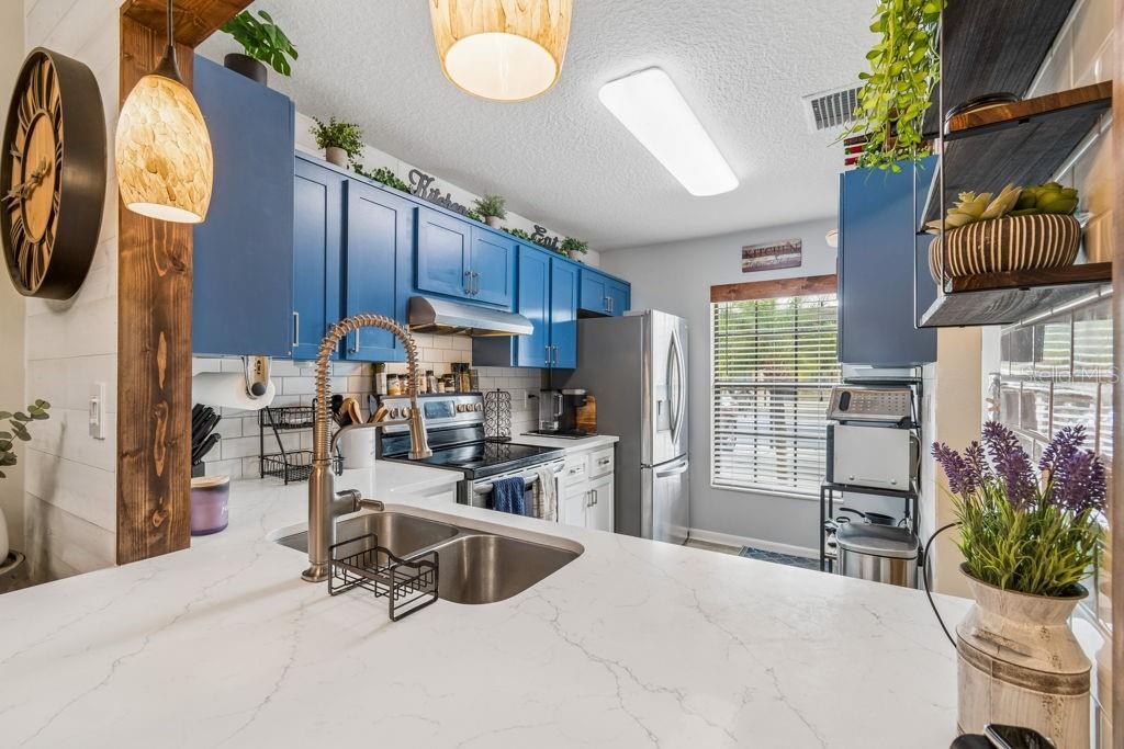 4753 Sunny Loop Holiday, FL 34690 - Photo 5 of 39 a kitchen with stainless steel appliances a stove a refrigerator a sink dishwasher a dining table and chairs with wooden floor