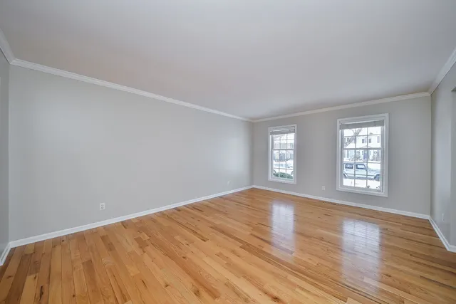 a view of an empty room with wooden floor and window