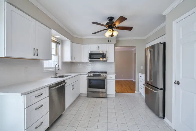 a kitchen with stainless steel appliances granite countertop a refrigerator a stove a microwave oven with white cabinets