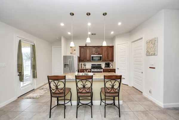 a kitchen with stainless steel appliances kitchen island granite countertop a dining table chairs and sink