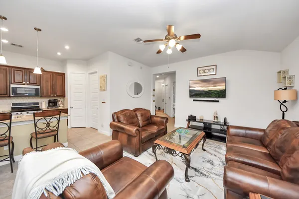 a living room with furniture kitchen view and a chandelier