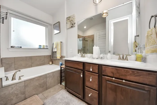a bathroom with a bathtub a double vanity sink and mirror