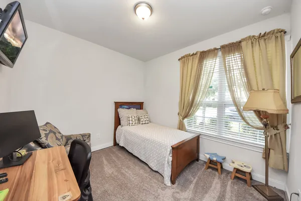 a bedroom with a bed and a flat tv screen on the dresser