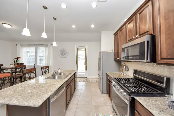 a kitchen with stainless steel appliances granite countertop a stove a sink and a microwave