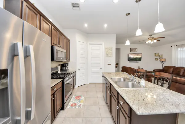 a kitchen with stainless steel appliances granite countertop a sink a stove and a refrigerator