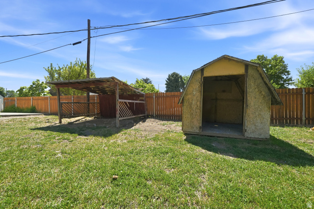546 West 200 South Payson, UT 84651 - Photo 8 of 45 Expansive grassy yard featuring a wood privacy fence, a covered open-sided structure with wood fencing, and an additional storage shed