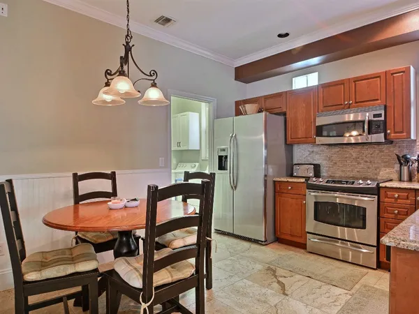a kitchen with stainless steel appliances a dining table chairs stove refrigerator and microwave