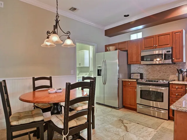 a kitchen with stainless steel appliances a dining table chairs stove refrigerator and microwave