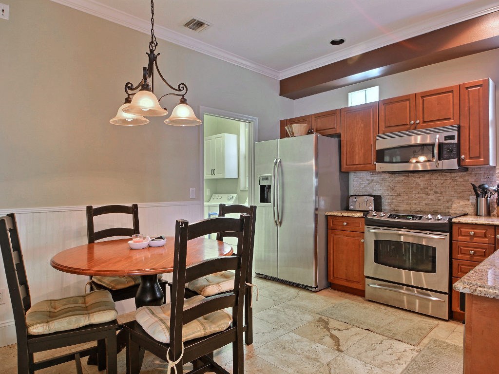 8705 Palm Tree Lane Vero Beach, FL 32963 - Photo 8 of 31 a kitchen with stainless steel appliances a dining table chairs stove refrigerator and microwave