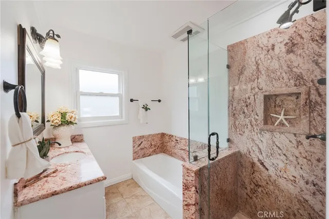 a bathroom with a granite countertop sink a mirror and shower