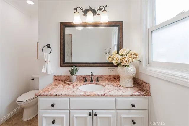 a bathroom with a granite countertop toilet sink and mirror