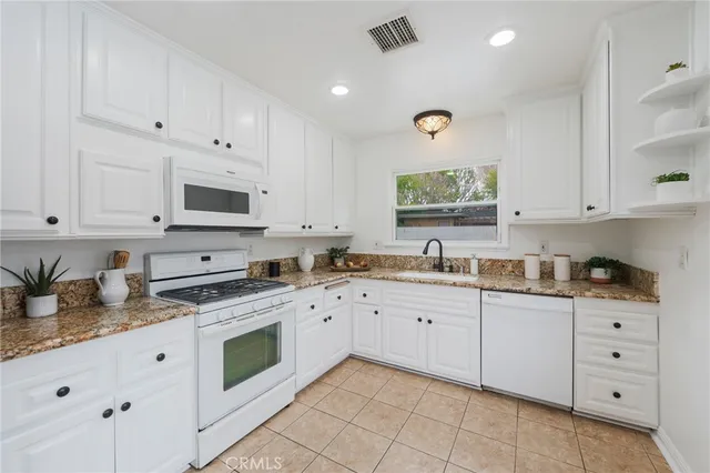 a kitchen with granite countertop white cabinets white stainless steel appliances with a sink and dishwasher