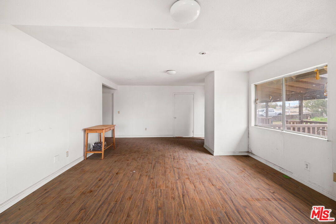 6906 Phelan Road Phelan, CA 92371 - Photo 11 of 42 a view of an empty room with a window and wooden floor