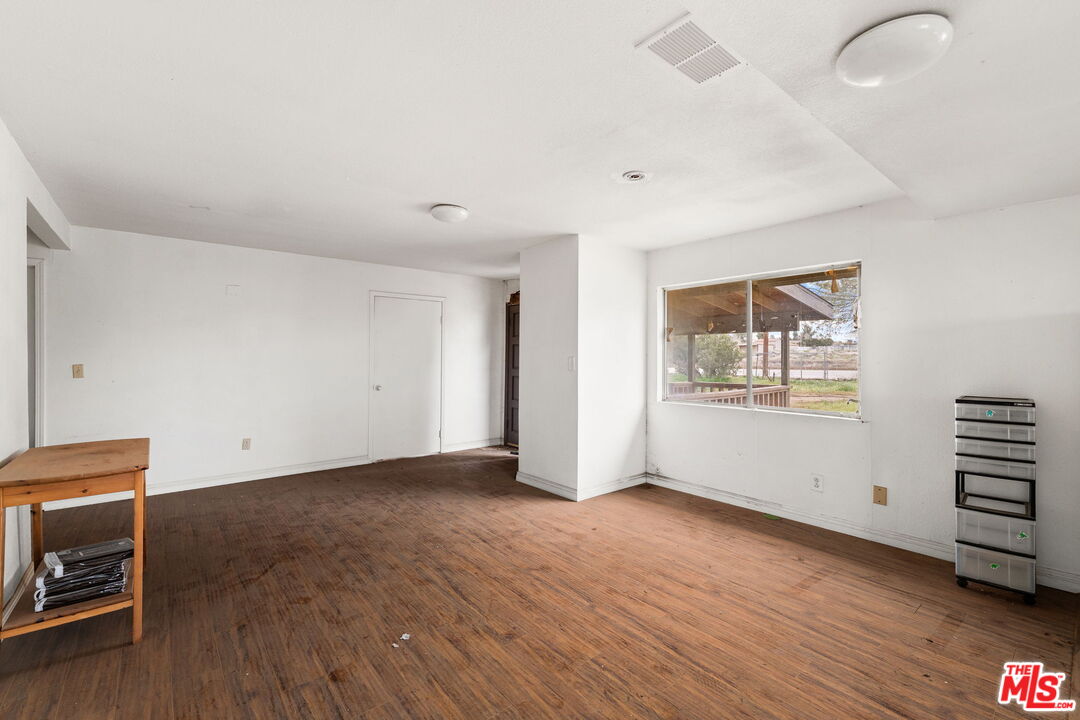 6906 Phelan Road Phelan, CA 92371 - Photo 12 of 42 a view of an empty room with wooden floor and a window