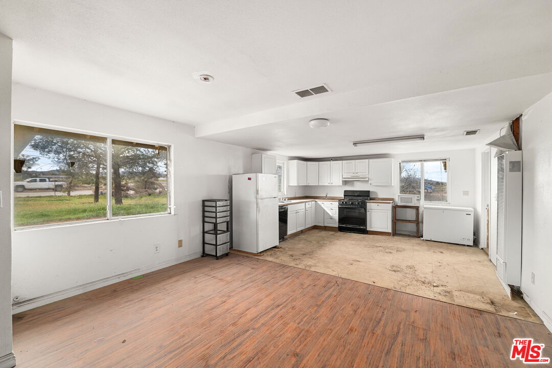 6906 Phelan Road Phelan, CA 92371 - Photo 8 of 42 a large white kitchen with wooden floors and white walls