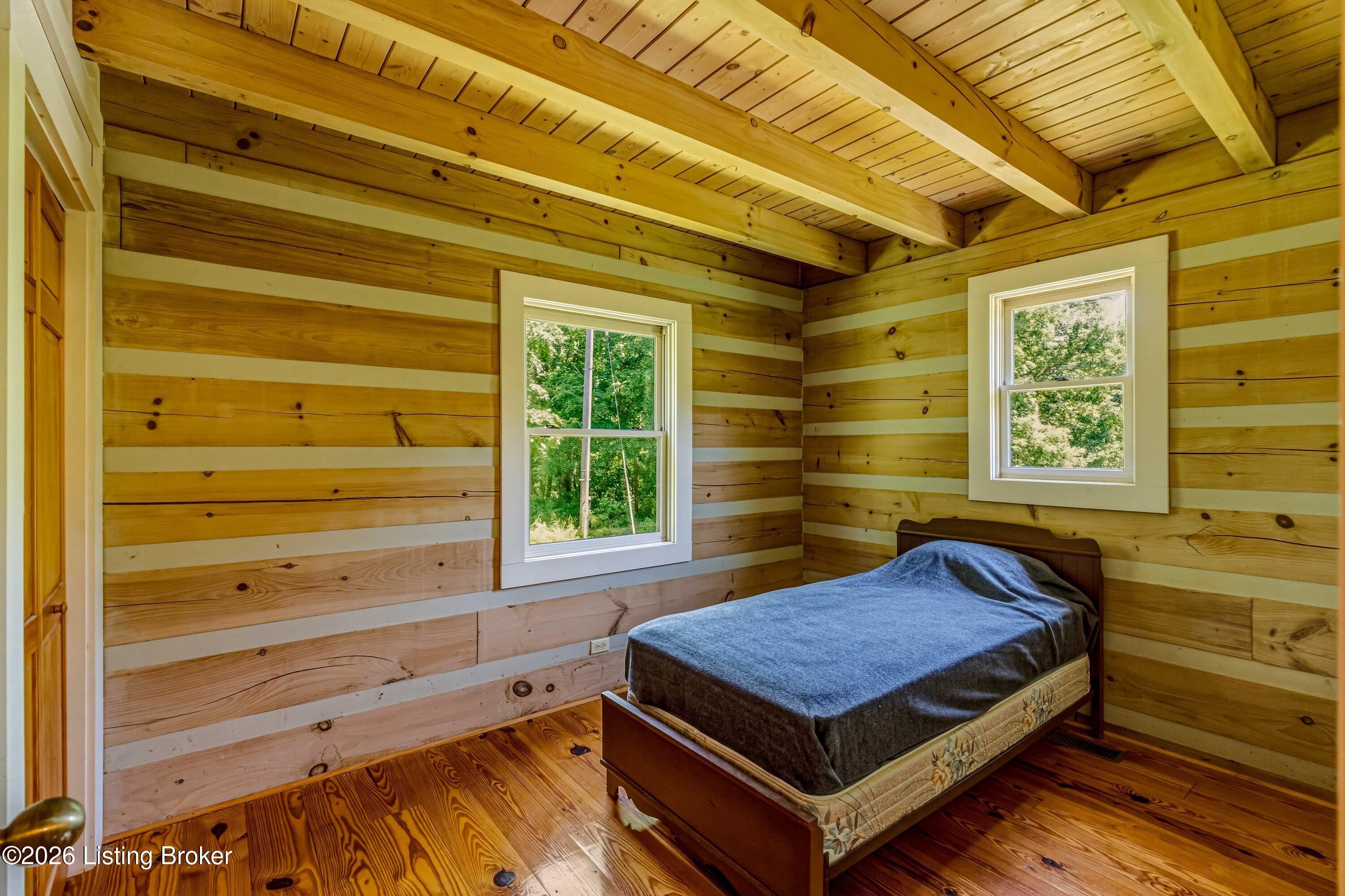 115 River Bend Road Glendale, KY 42740 - Photo 20 of 35 A cozy bedroom with log walls and natural light framed by the trees outside.