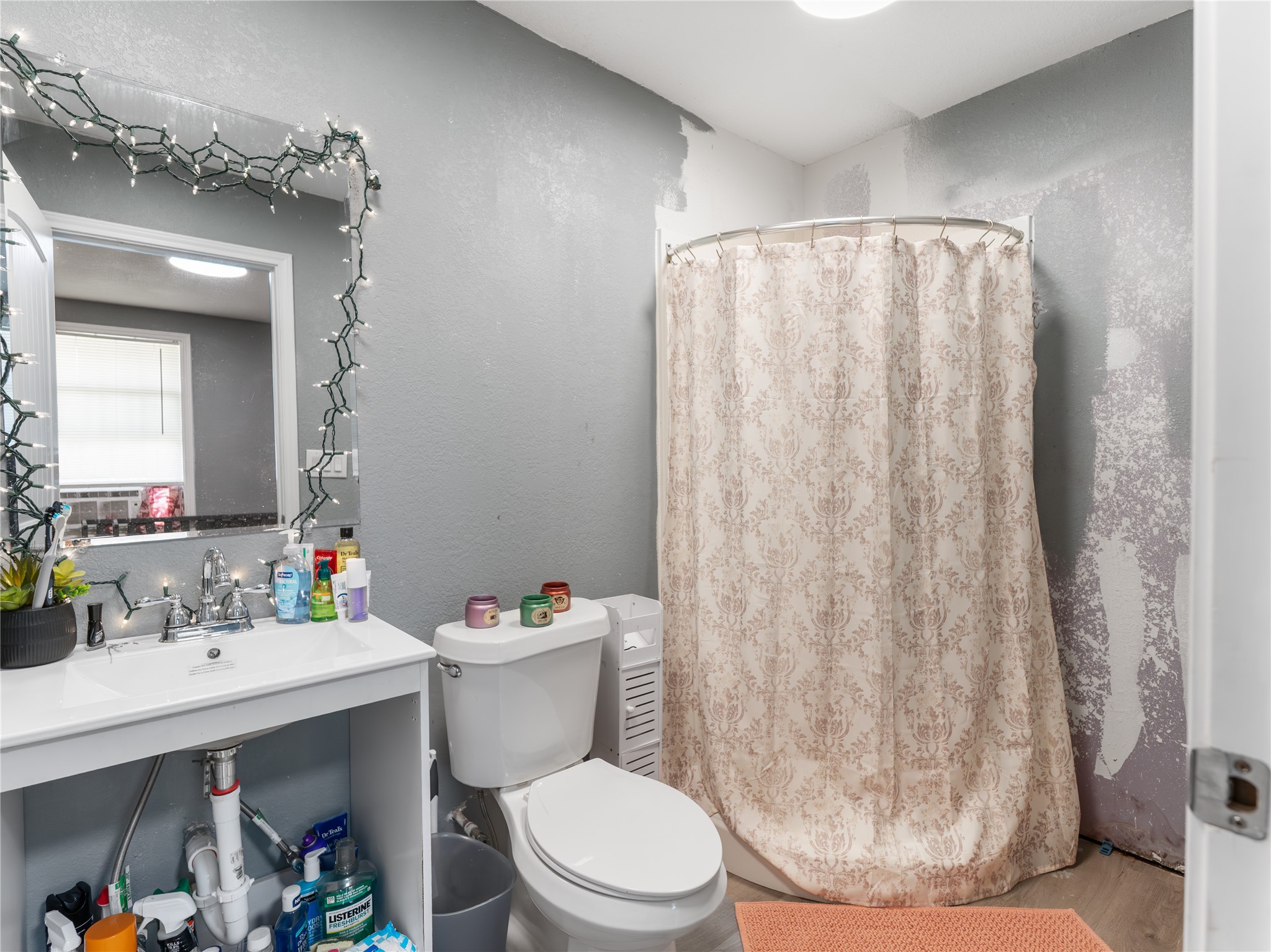 496 James Street Clute, TX 77531 - Photo 17 of 45 a white toilet sitting next to a bathroom sink and a shower curtain