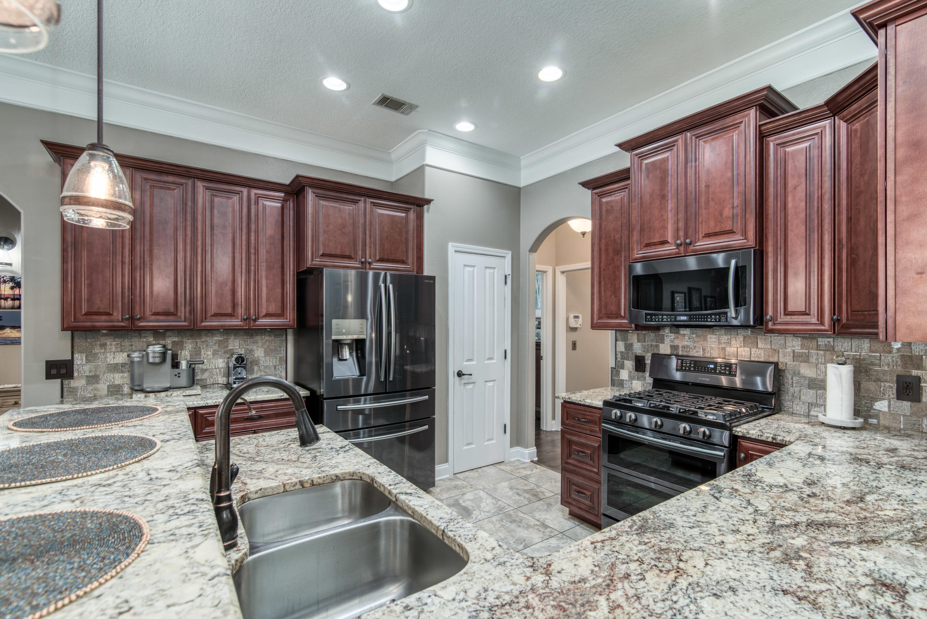 4563 Pfitzer Circle Crestview, FL 32536 - Photo 17 of 79 a kitchen with kitchen island granite countertop wooden cabinets a stove a oven and a refrigerator with wooden floor