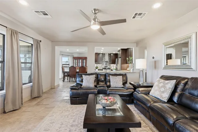a living room with furniture kitchen view and a large window